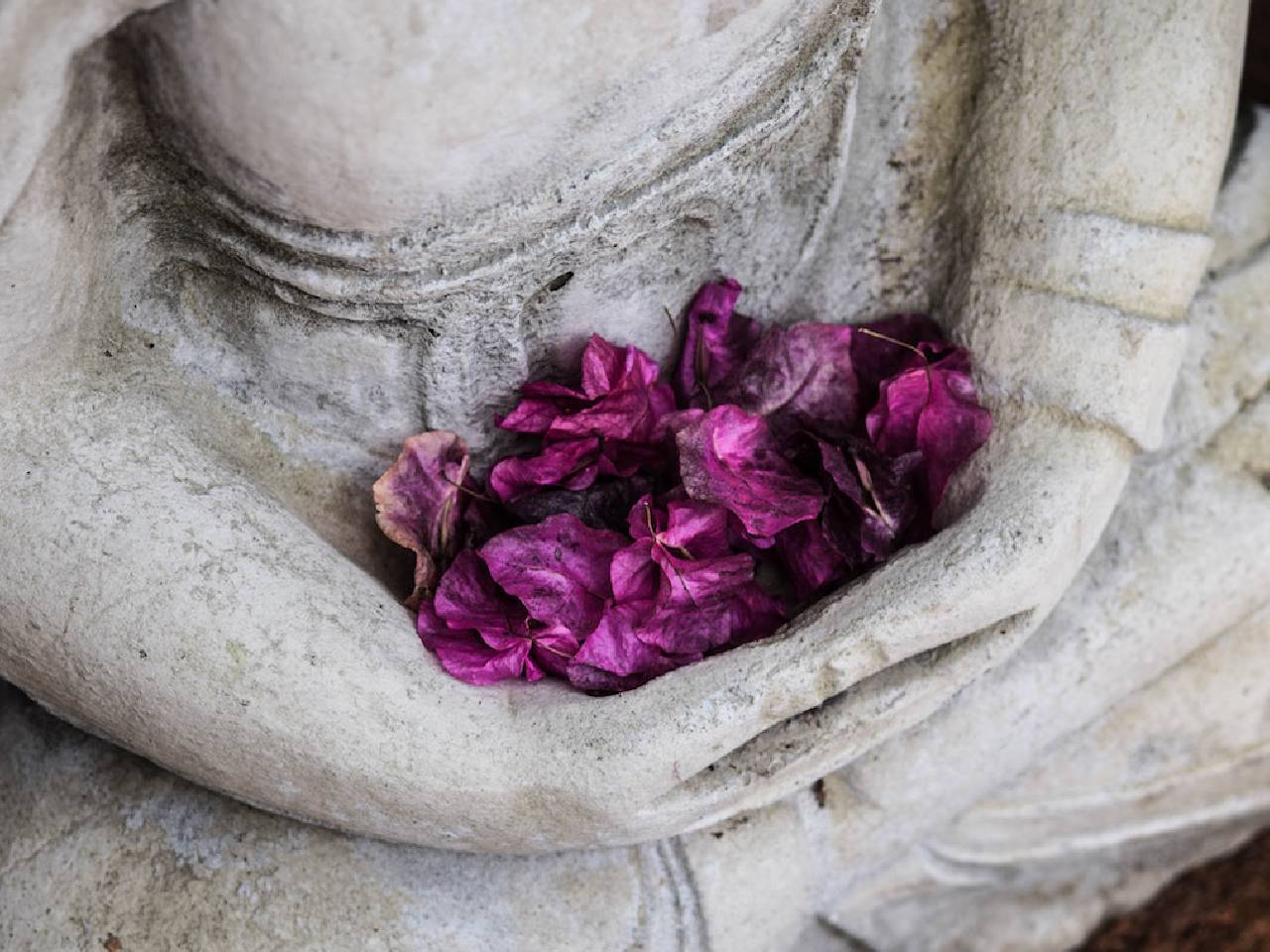 seated statue with flower petals in its hands