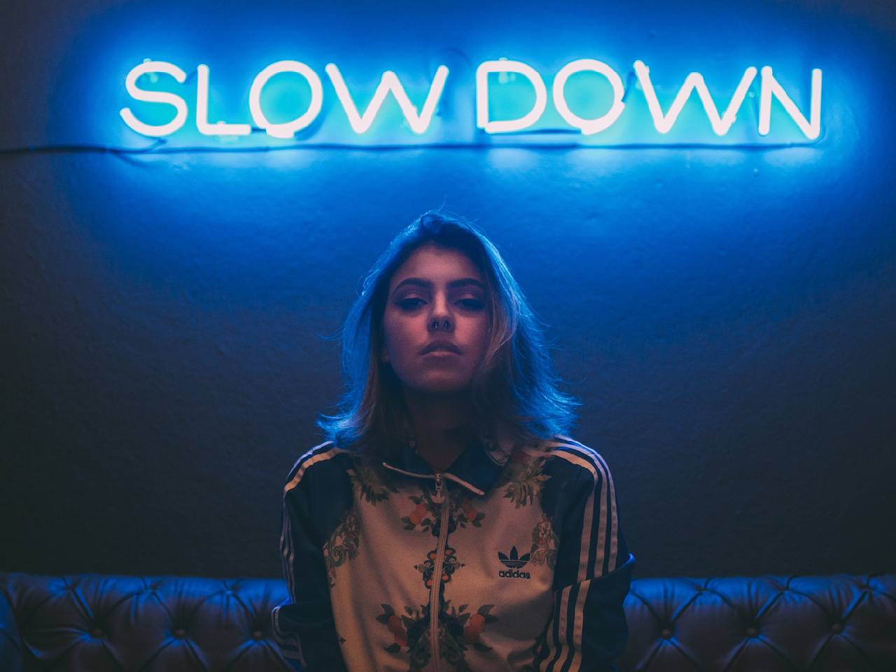 young women in front of a neon slow down sign