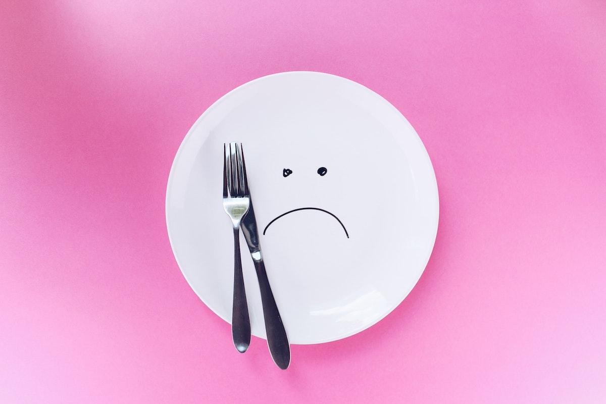 stainless steel fork and knife on plate with unhappy face